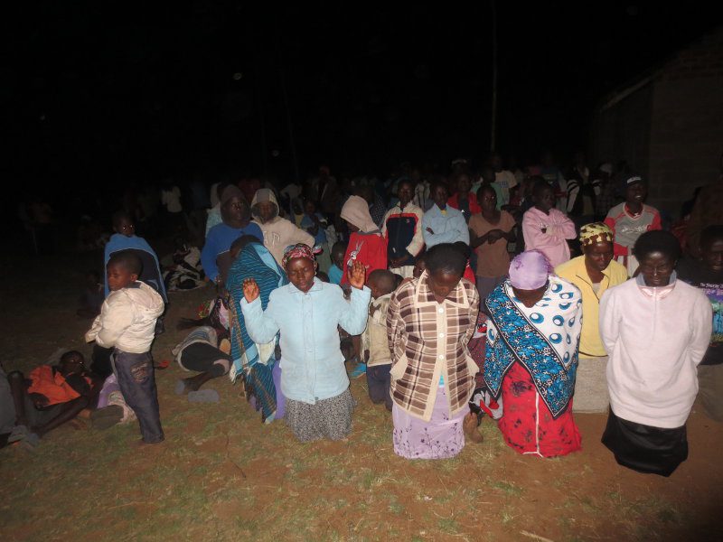 Ghanaian Christians kneeling together on the ground praying and worshiping God
