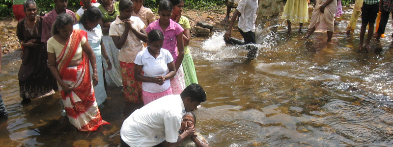 Sri Lankan woman baptized in river by Christian missionary while others watch