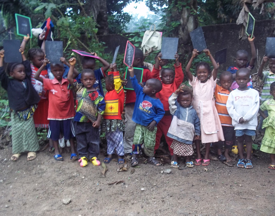 Guinean children standing outside each holding up their own personal chalkboard