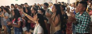 Colombian Christians standing together some with their eyes closed worshiping God