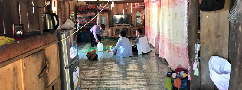 Cambodian woman husband and wife sitting on the carpet of their living room with a guest