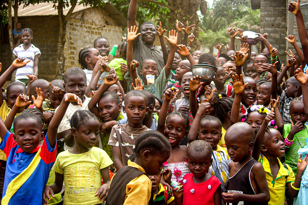 Sierra Leonean children with their hands up and smiling
