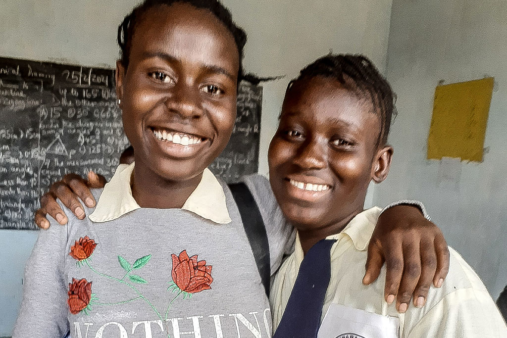 Two Gambian Christian students with their arm around the other smiling