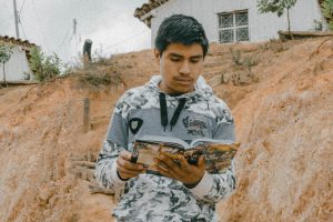 Mexican teenager standing outside reading a Christian action Bible