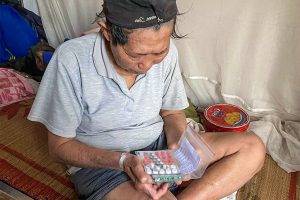 Vietnamese man sits on mat holding medicine