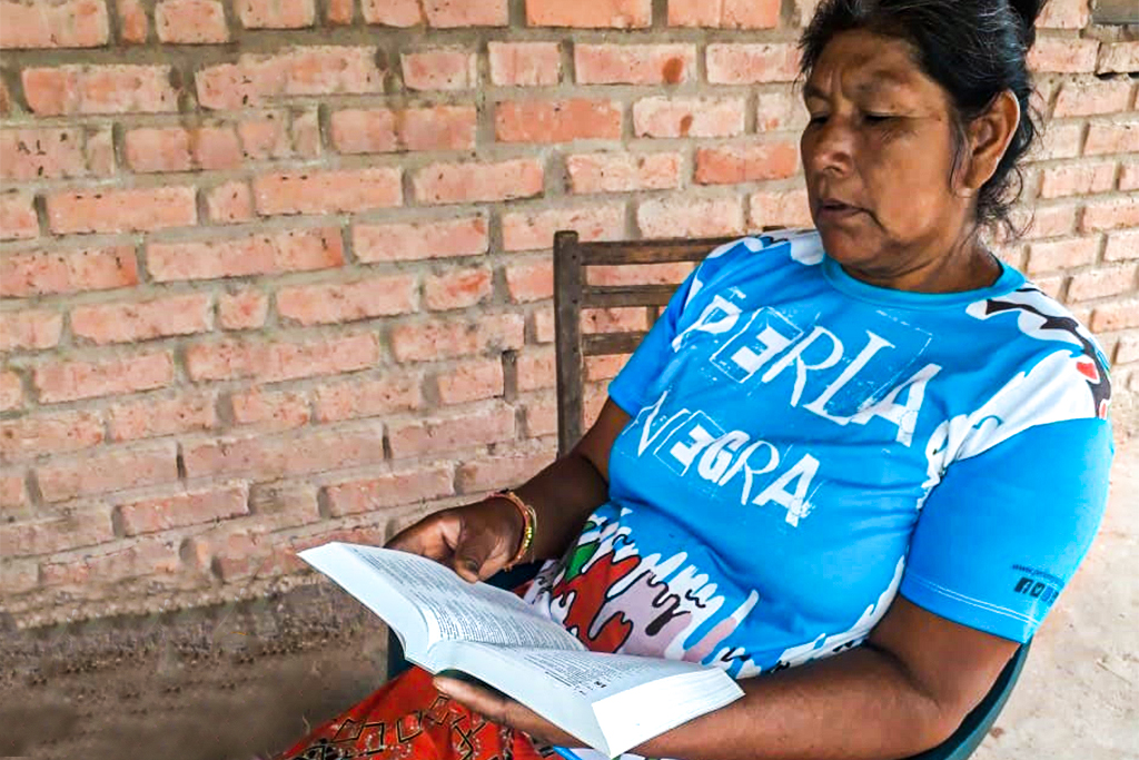 Argentinian woman sits in wooden chair reading the Bible