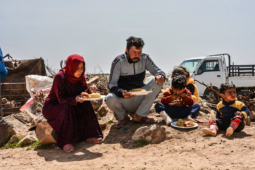 A Jordanian family sits eating lunch in a barren area