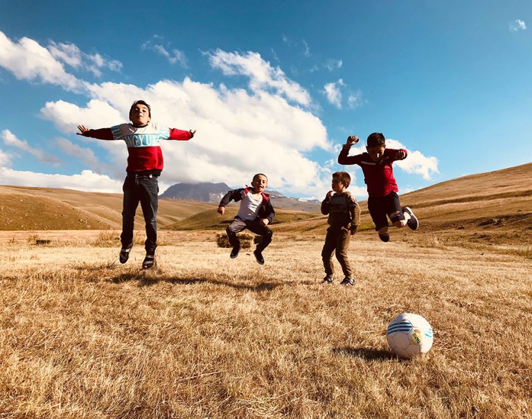 Young Armenian boys in a dry plane jumping while taking a break from playing soccer