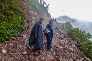 Two Nepalese Christian men walking on a rocky road on the side of a steep mountain