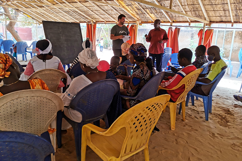 Christian missionary leads a bible study for Chadian teens under a pavilion made of canvas