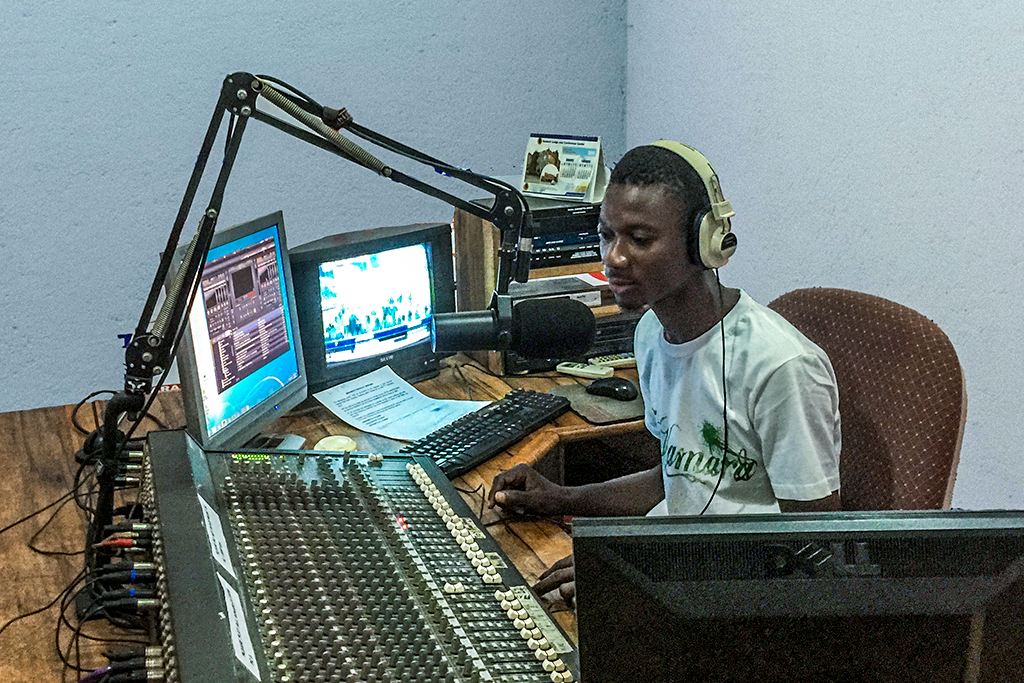 Young Ghanaian sits in studio producing a Christian radio show