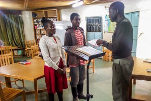 Kenyan teenage boy and girl receive Bible teaching from a Christian missionary