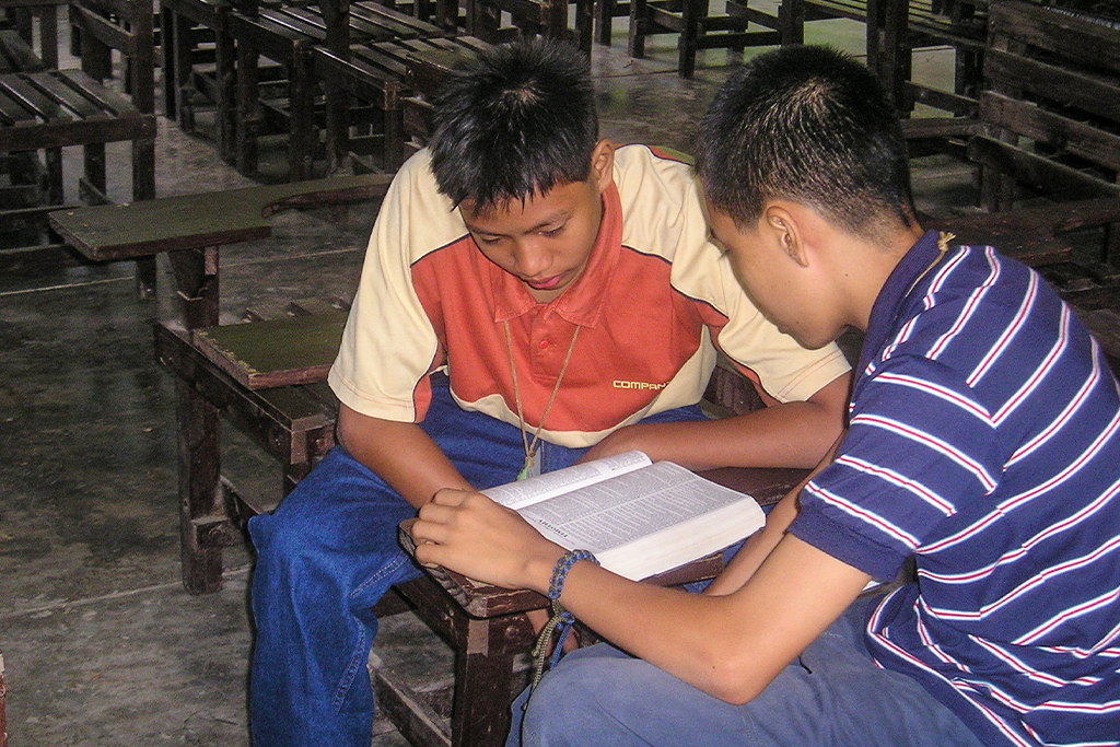 Two Filipino teenage boys study the Bible together after school