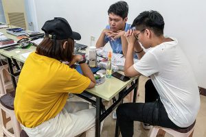 Three young adult Chinese Christian believers take a break to pray while working on a project