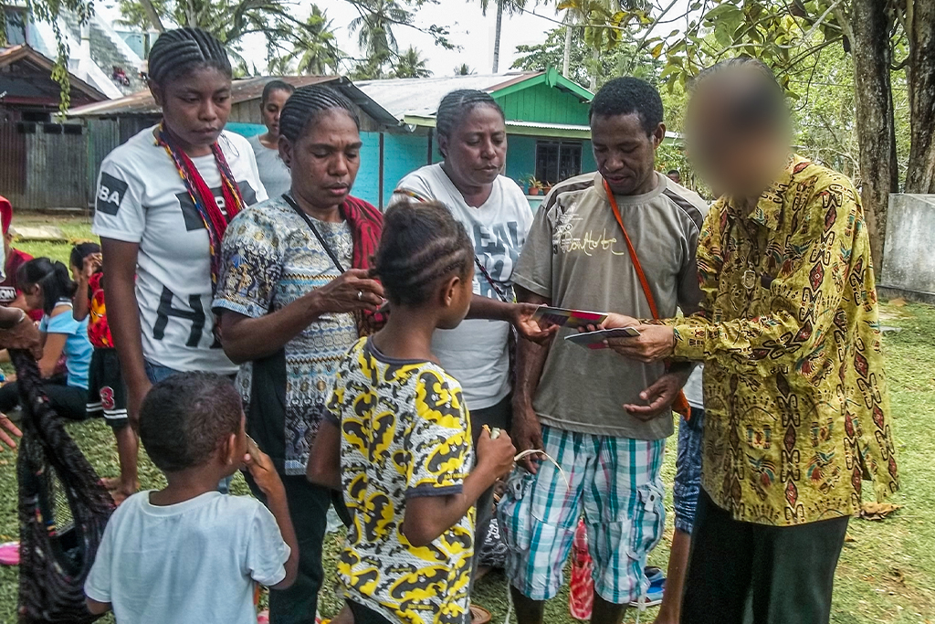 Christian missionary in Indonesia passes out gospel tracts to adults