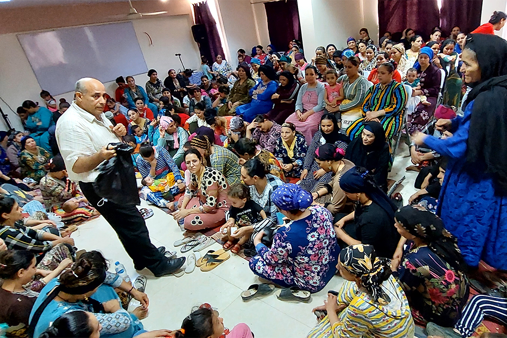 Christian missionary speaking to a large group of women and children about the gospel