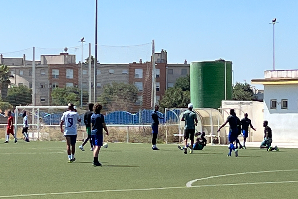Refugees in Spain playing soccer on a turf field
