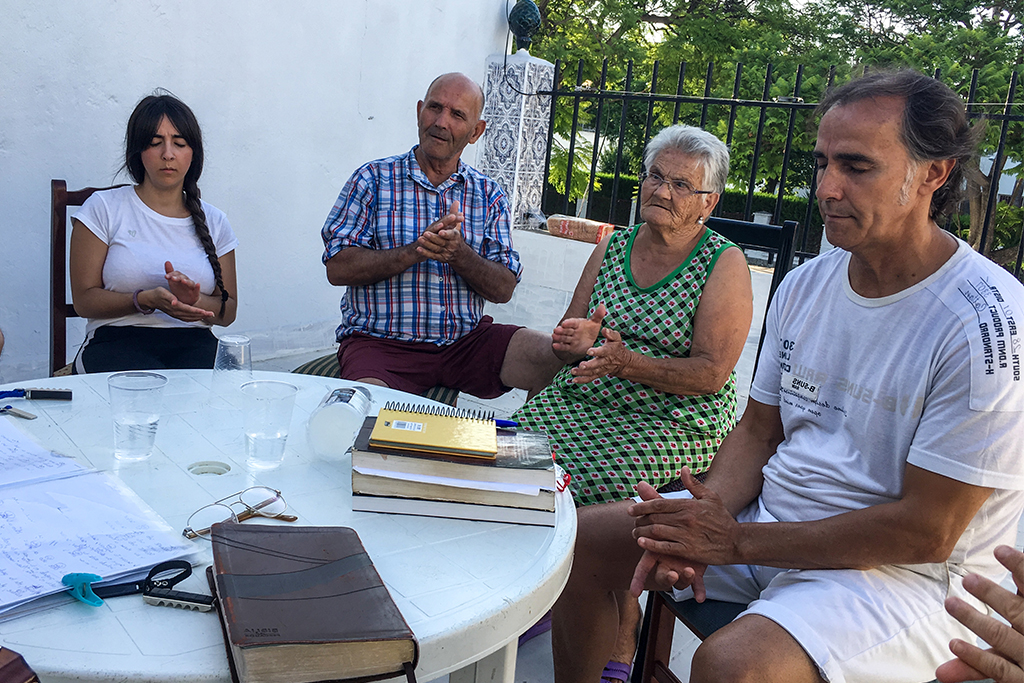 European Christians sitting outside at a circular table praying during a bible study