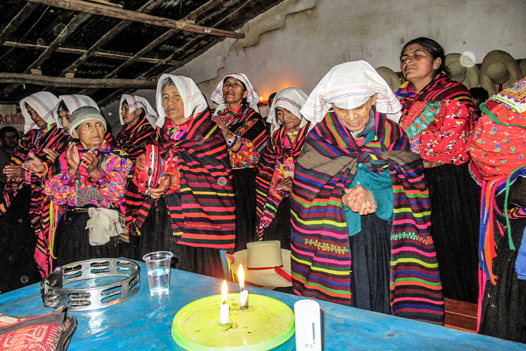 Peruvian Christian women wearing traditional clothes gathered together praying