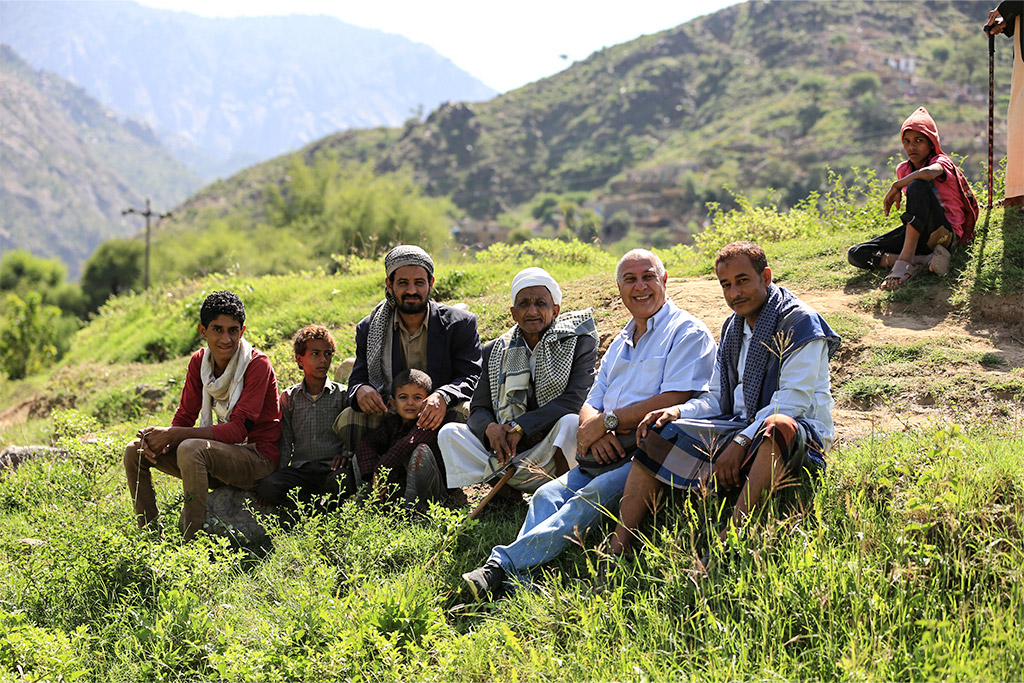 Lebanese men and boys sitting on a grassy mountainside with other mountains in the background