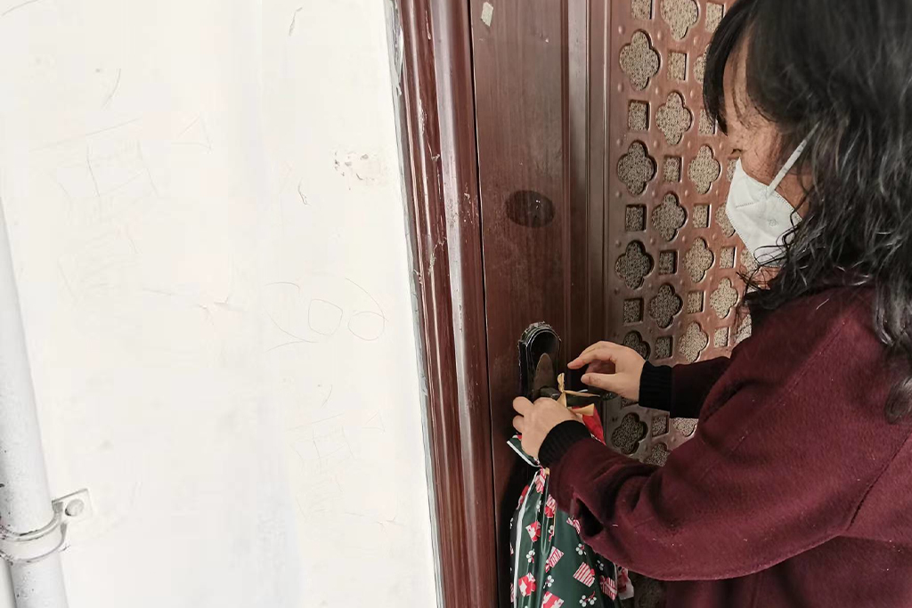 Chinese woman wearing a mask locks the door to her house