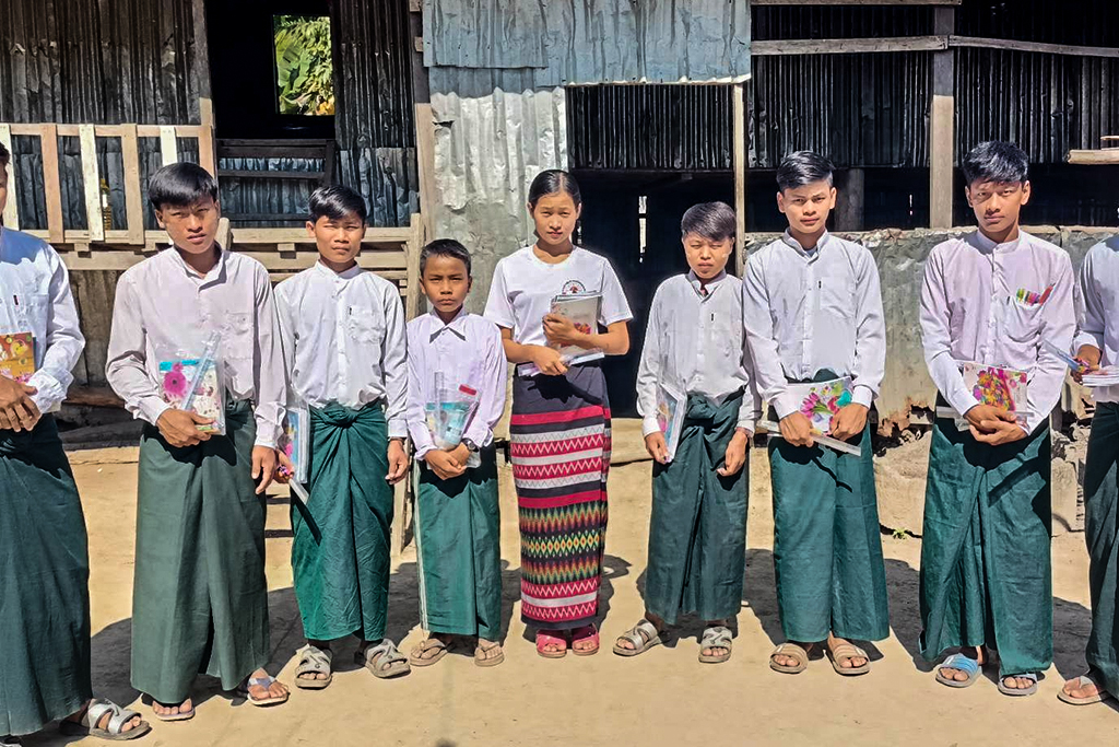 Young teenage students standing outside holding their notebooks and wearing their uniforms of white tops and green bottoms