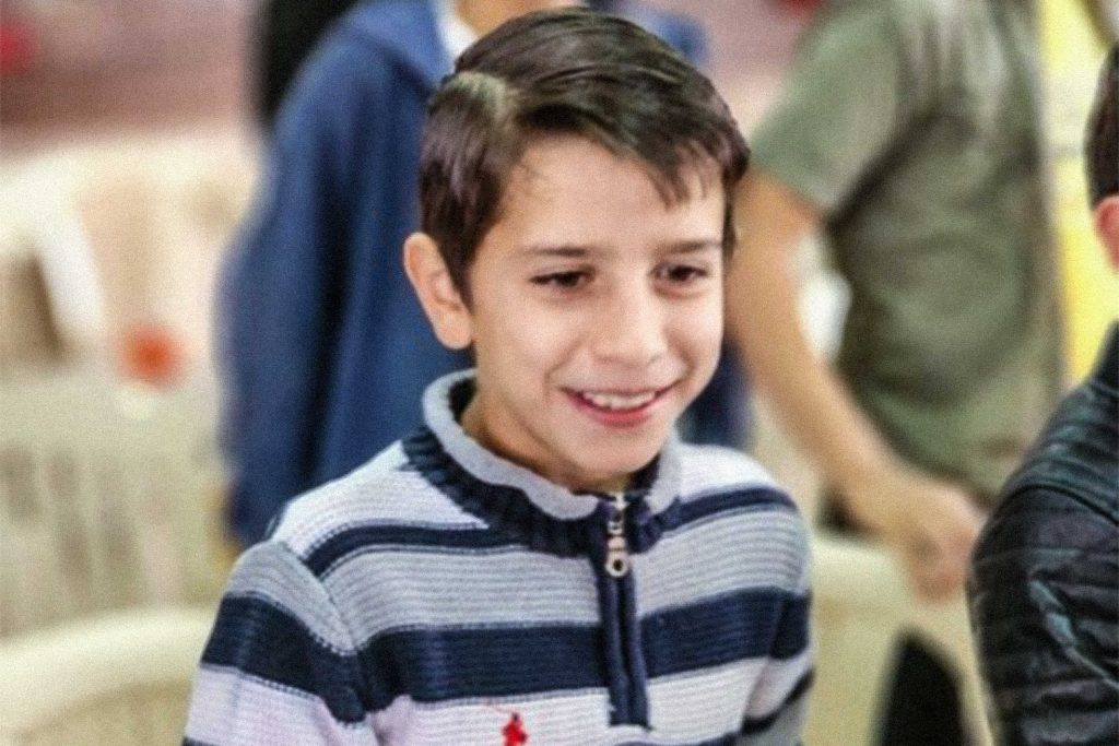Lebanese boy wearing a quarter-zip sweatshirt smiling