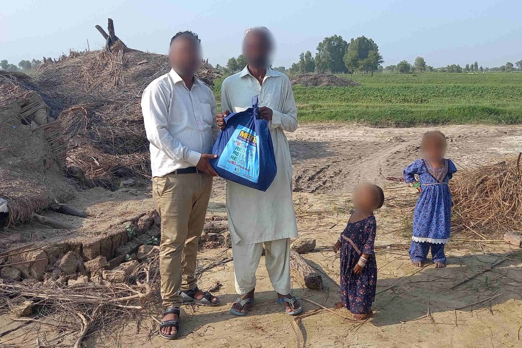Pakistani Christian worker gives food to man so that he and his two children can eat