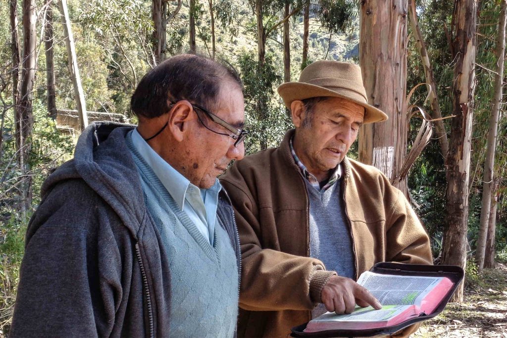 Peruvian missionary reads a passage of the Bible to a man in the woods
