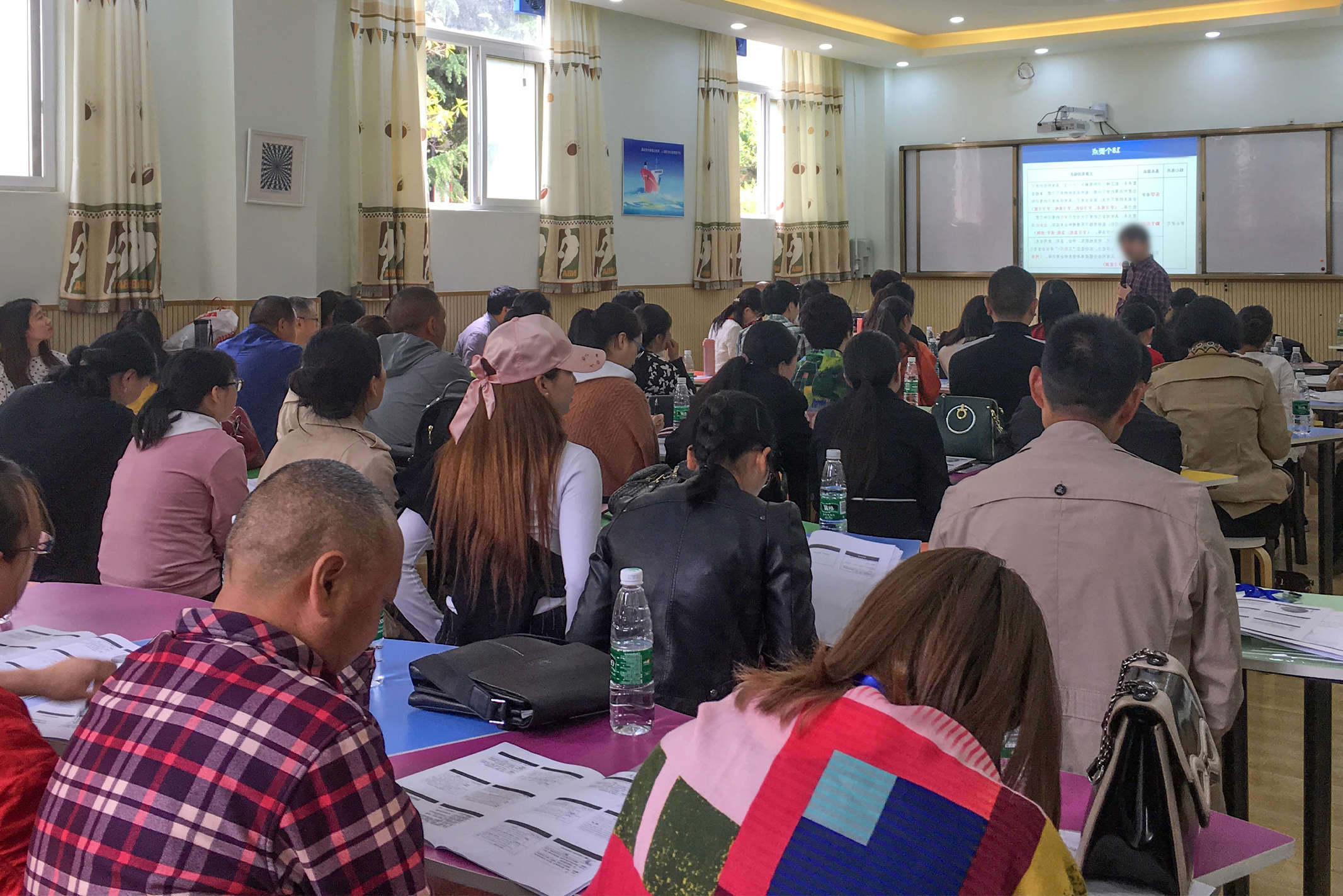 Chinese Christians sitting in rows behind desks listening to a speaker talk at a training conference