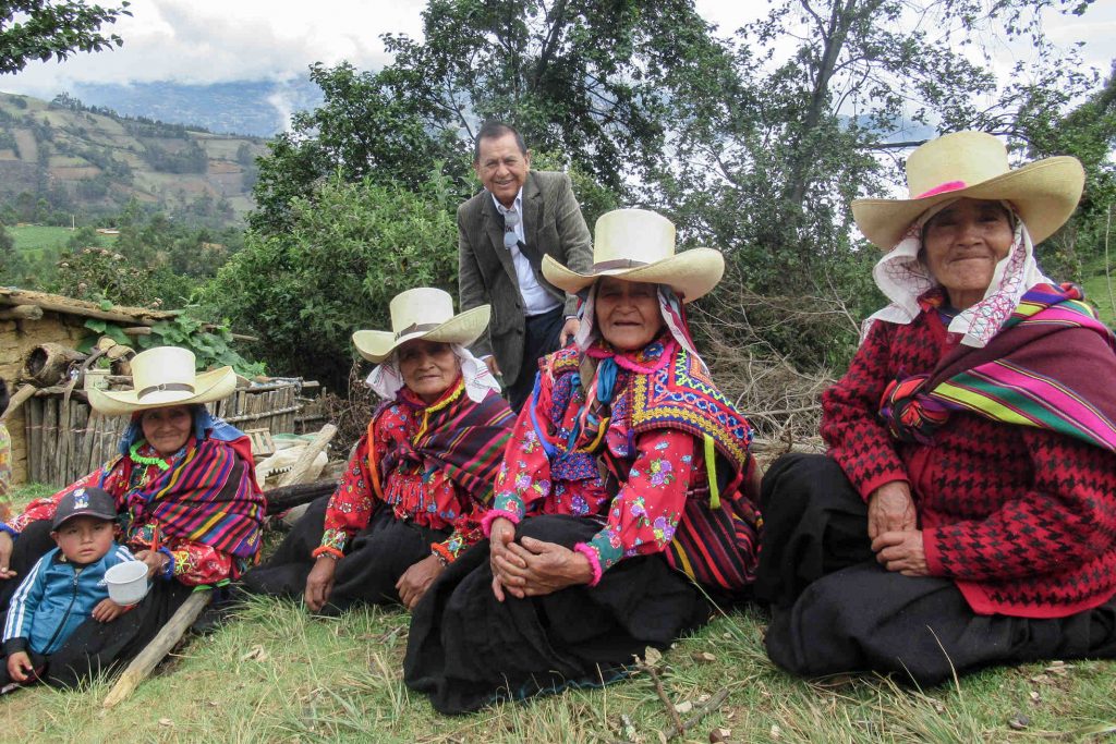 Peruvian women sitting on a hill wearing traditional clothes with large hats