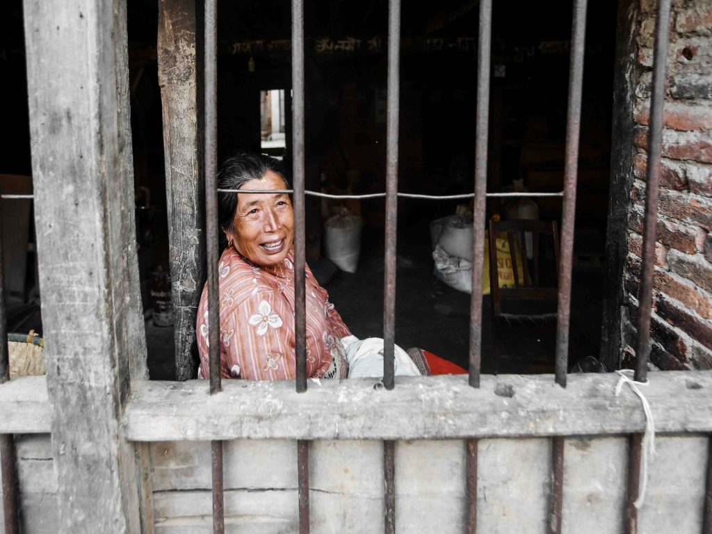 Elderly Laotian woman sitting behind a barrier made of steel bars