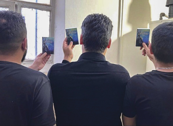 Three Iranian men holding up booklets