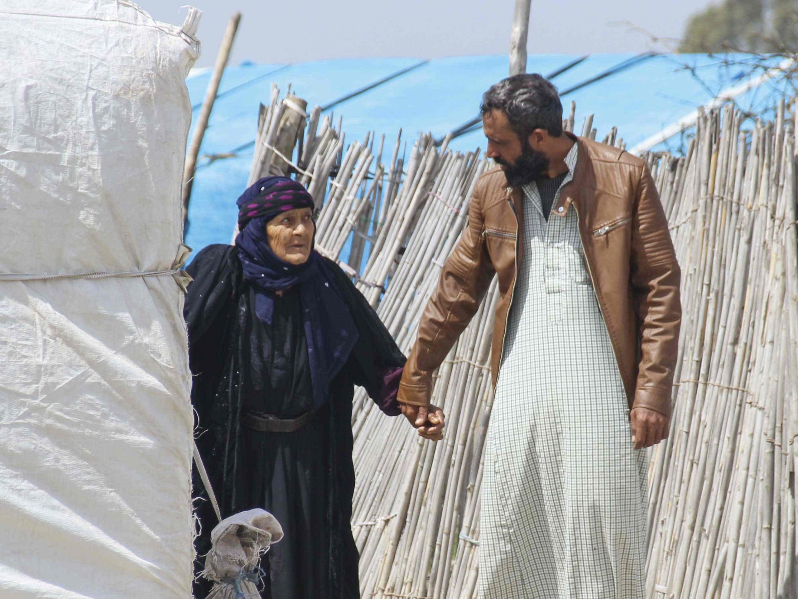 Christian missionary holds the hand of an elderly refugee woman in a refugee camp