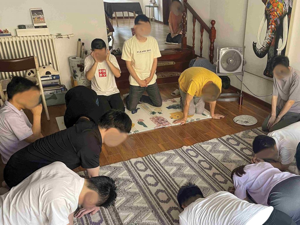 Christians in China kneeling on the floor in a circle praying together in a house