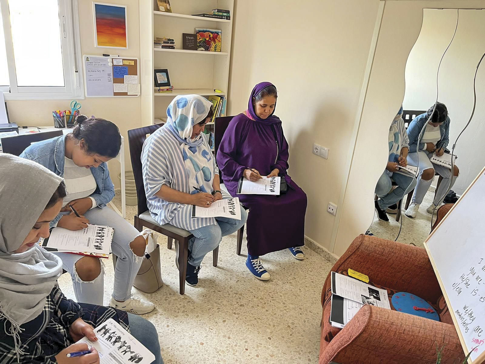 Middle Eastern refugees in an apartment in Greece learning how to speak a new language.
