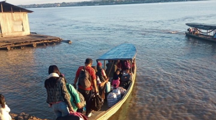 Peruvians board a small wooden boat on a river